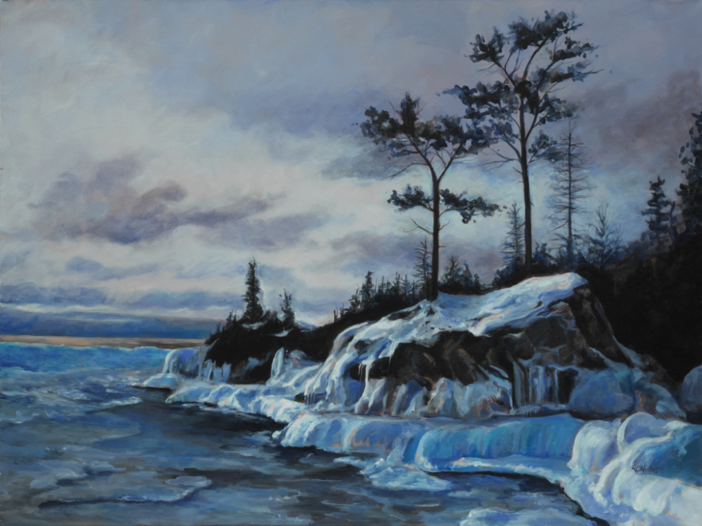 Icy, snow covered cliff surrounded by water in early evening.